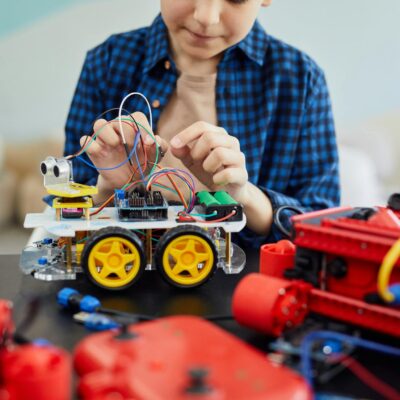 Young boy engaged in assembling a robotic toy car, showcasing early interest in STEM education.